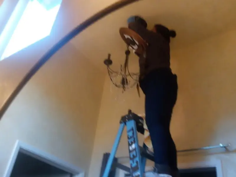 Electrician installing a chandelier in a Valdosta residence